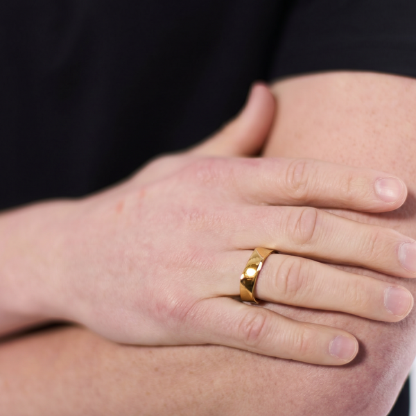 Hand wearing a gold ring with a blurred background